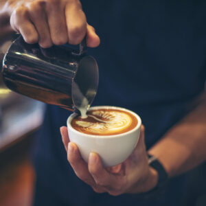 Close-up of hands barista make latte coffee art paint