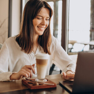 Young business woman working online in a cafe and drinking coffee